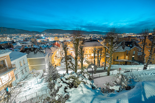 Beautiful evening panorama of Bergen, looking from above between the houses. Looking down between the houses towards funicular station. Snow on the roofs, beautiful setting.
