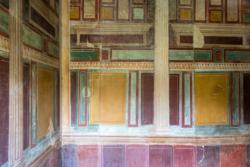 Looking at ancient wall painting at the Tempel of Isis in the city of Pompeii. When the Temple of Isis was discovered by excavators its decoration and furnishings were almost intact, thereby contributing decisively to introduce Pompeii to the world. Pompeii is an ancient Roman city that was buried under 4 to 6 m (13 to 20 ft) of volcanic ash and pumice in the eruption of Mount Vesuvius in AD 79. Today Pompeii is a UNESCO World Heritage Site and is one of the most popular tourist attractions in Italy.
