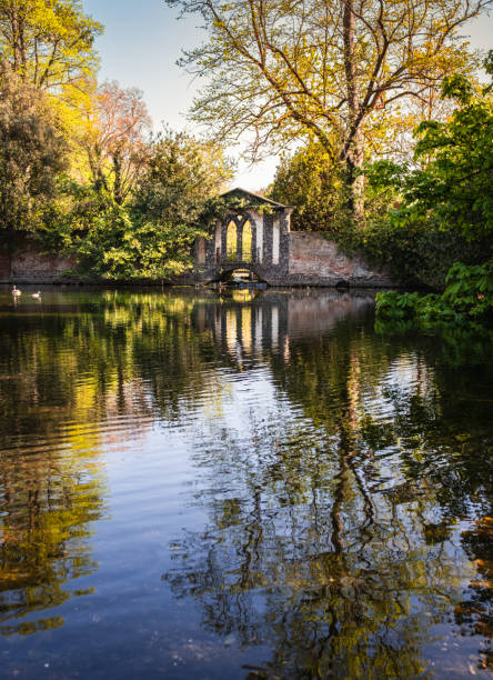 View of park with pond in  spring with trees and arch in background
