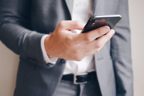 istock Midsection of a businessman using his mobile phone 2056391675