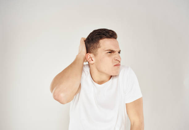 istock A puzzled man touches himself with his hands on a light background in a white T-shirt 2056453191