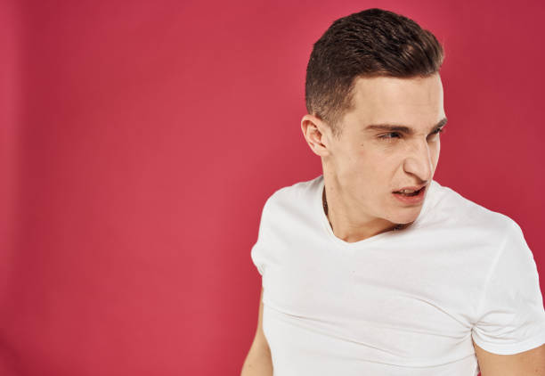emotional man in white t-shirt studio dissatisfaction red background. High quality photo