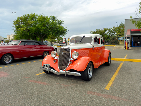Buenos Aires, Argentina - Feb 25, 2024: Old white and orange 1934 Ford V8 model 40 coupe 5 window customized street rod at a classic car show in a parking lot. Copy space