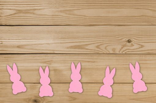 Easter bunnies on wooden surface. DIY paper crafts for Easter holidays. Preparation and celebration. Simple decor for home, children's room, school, birthday. Copyspace