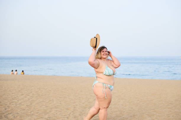 istock Happy plus size woman in bikini taking off straw hat 2056526288