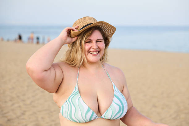 istock Cheerful overweight woman in bikini on beach 2056527318