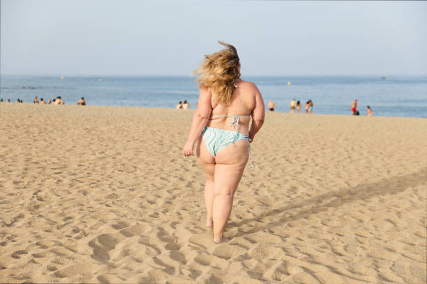 веселая женщина с лишним весом бежит по песчаному пляжу на фоне моря - beauty beautiful bikini caucasian стоковые фото и изображения