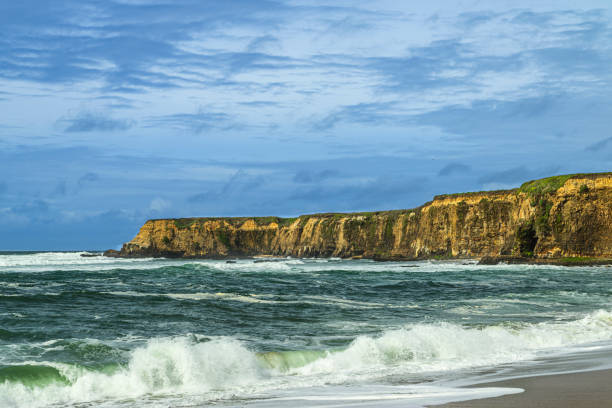 Turbulent ocean waves breaking along the Pacific coast under a cloudy sky, as a storm passes through the area.Taken in Davenport, California, USA