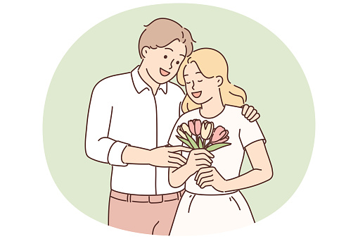 Loving man hugging woman giving bouquet flowers in honor of anniversary relationship or Valentine Day. Loving bride and groom with wedding flowers in hands during festive ceremony or birthday party