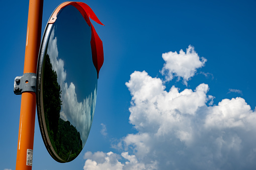 Midsummer blue sky. Clouds are reflected in the curved mirror.
