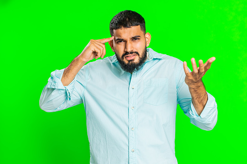 You are crazy, out of mind. Confused Indian man pointing at camera and showing stupid gesture, blaming asking some idiot for insane plan, bullying. Arabian guy isolated on green chroma key background