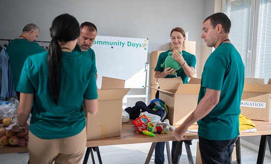 Community Days. Multi-generation volunteers arranging charitable donations in community center.