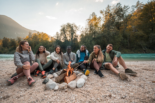 Embraced by the beauty of the forest, a multiracial group of friends finds solace and joy around a crackling bonfire. Their laughter and togetherness echo through the trees, creating memories that will last a lifetime.