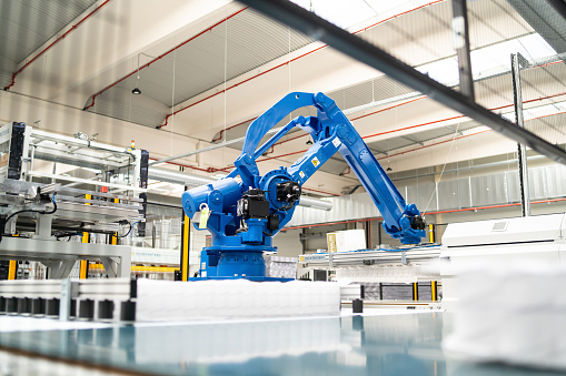 A blue colored robotic arm working in an industrial factory for automated production
