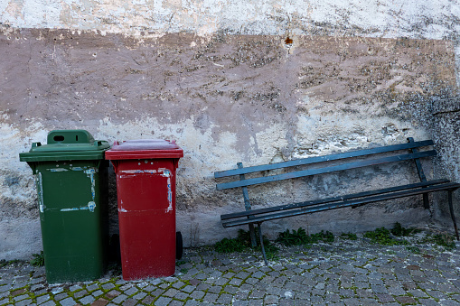 Castrovalva, Italy Red and green garbage bins next to a broken bench.