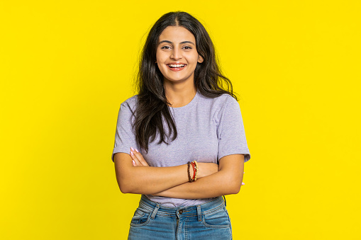 Cheerful lovely happy young Indian woman smiling friendly glad expression looking at camera dreaming resting relaxation feel satisfied good news. Arabian girl isolated on yellow studio background