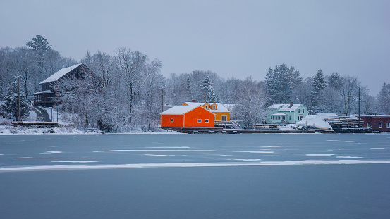 Colorful houses by a frozen lake, during a winter snowstorm.