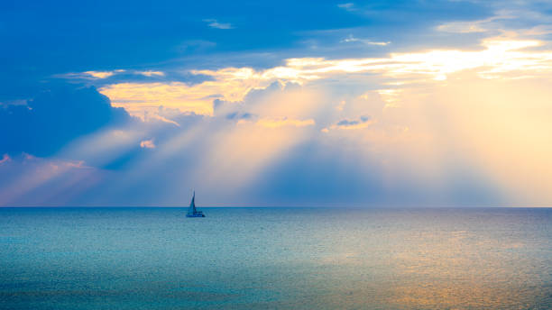Single sailboat in the Caribbean ocean during a dramatic sunset.