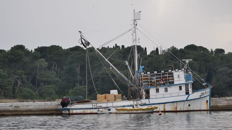 An old fishing trawler at the pier. Deserted pier in the port. Small ripples on the surface of the sea. Rovinj, Croatia - February 29, 2024