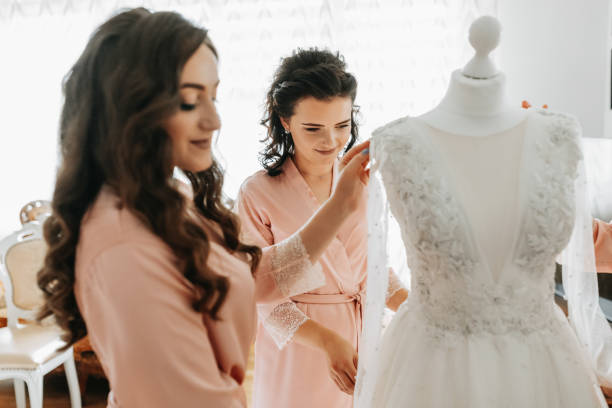 istock bride's girlfriend prepares the bride for her wedding day. The bride's girlfriend helps secure the bride's wedding dress before the ceremony. 2056883443