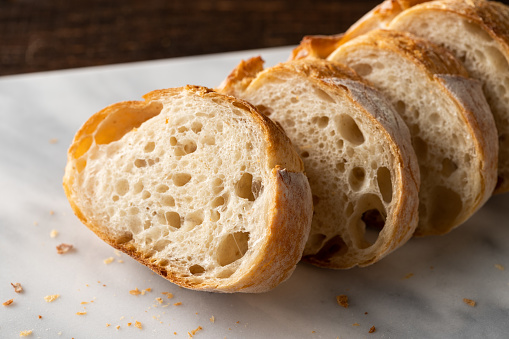 bird's eye view of three loaves of bread, one of which is cut in half and allows you to see the crumb of bread.