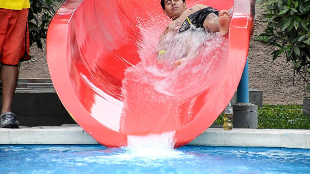 A young man slides through a slide towards the pool