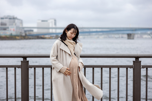 Portrait of pregnant woman at the port of Tokyo Bay - looking at her belly