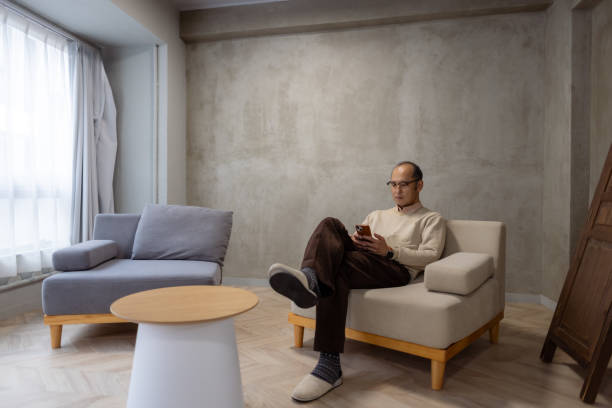 Man relaxing in living room, using smart phone