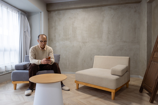 Man relaxing in living room, using smart phone
