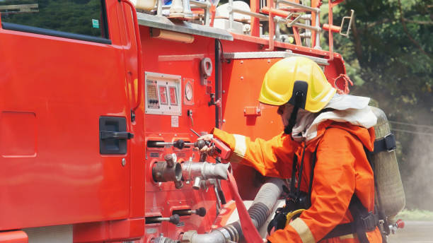 istock Fireman prepare equipment fighting extinguisher at fire engine truck. Firefighter fighting with smoke flame using fire hose, tube, chemical water foam spray at truck. Fireman wear hard hat protection 2056993039