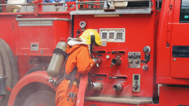 istock Fireman prepare equipment fighting extinguisher at fire engine truck. Firefighter fighting with smoke flame using fire hose, tube, chemical water foam spray at truck. Fireman wear hard hat protection 2056993080