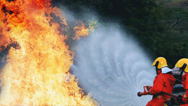 istock Firefighter Rescue team training in fire fighting extinguisher. Teamwork Firefighter fighting with flame using fire hose chemical water foam spray engine. Fireman teams wear hard hat safety uniform 2056993641