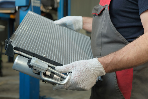 An auto mechanic prepares a new radiator for installation.