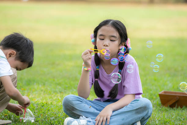 istock Children sitting in the park with blowing air bubble, Surrounded by greenery and nature 2057082995