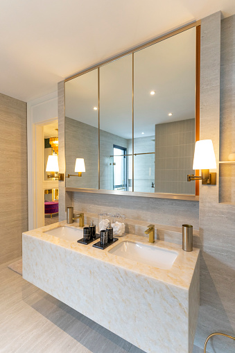 A luxury bathroom with duo sinks and marble top. Large mirror on wall.