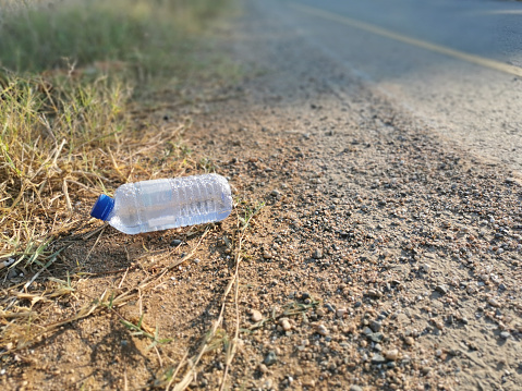 Plastic bottle on the floor beside the main road with copy space on the right side. Concept for Effects of Littering on the Environment.