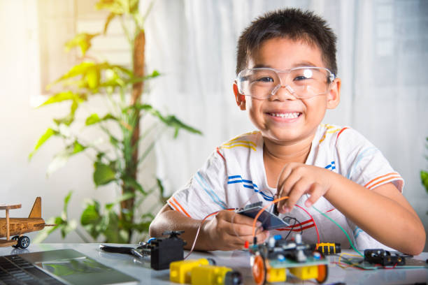 istock Asian kid boy plugging energy and signal cable to sensor chip with open-source hardware and software robot car 2057138569
