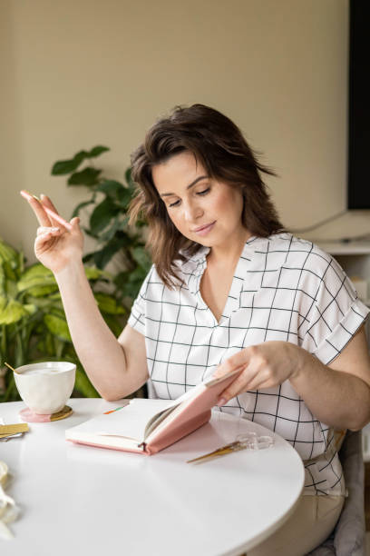 istock Smiling young business woman planning work making notes in paper diary at comfortable home 2057144367