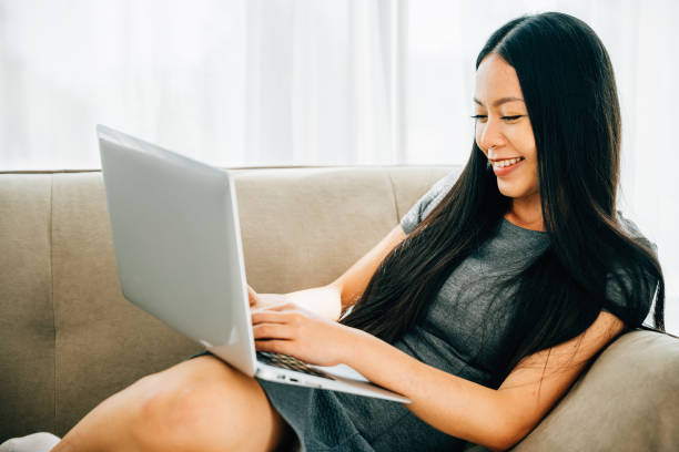 istock Woman on sofa enjoys using laptop for ecommerce learning watching videos 2057147210