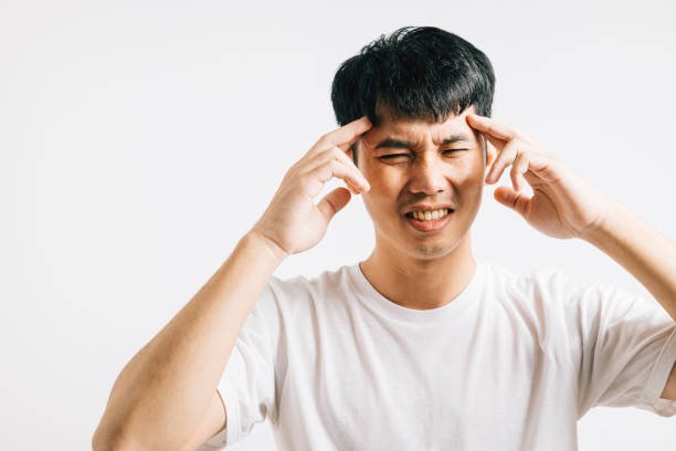 istock Asian man, battling stress and throbbing headache, holds head with a pained expression 2057154808