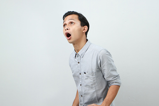 Funny shocked and surprised face of asian Indonesian man, open wide mouth say wow, on isolated backgorund