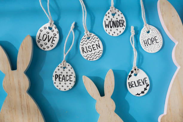 Group of wooden bunny ears and clay Easter eggs with words RISEN HOPE BELIEVE PEACE LOVE WONDER White air dry clay for making decor to EASTER holiday. Creating hobby recreation activity that involves fingers. DIY crafting Modern art