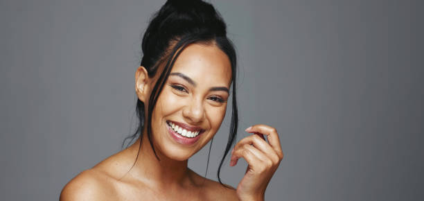Face, skincare and happy woman wink in studio isolated on a gray background. Portrait, natural beauty and model flirting in spa facial treatment for aesthetic, glow and cosmetic wellness for health la cara, el cuidado de la piel y la mujer feliz guiñan el ojo en el estudio aislado sobre un fondo gris. retrato, belleza natural y modelo coqueteando en el tratamiento facial de spa para la estética, el brillo y el bienestar cosmético para la salud