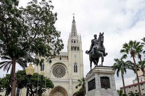 View of Parque Seminario (Seminar Park), also known as Bolivar Park or Iguanas Park, a small and traditional public urban park located in the center of the city of Guayaquil, with the monument to Simón Bolivar in the middle of the park and the Metropolitan Cathedral of Guayaquil in the background.