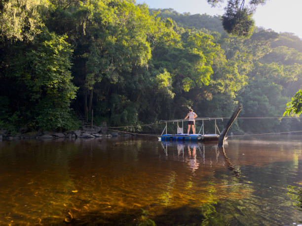 istock Fit woman crossing a river on a floating raft using a rope. 2057200836