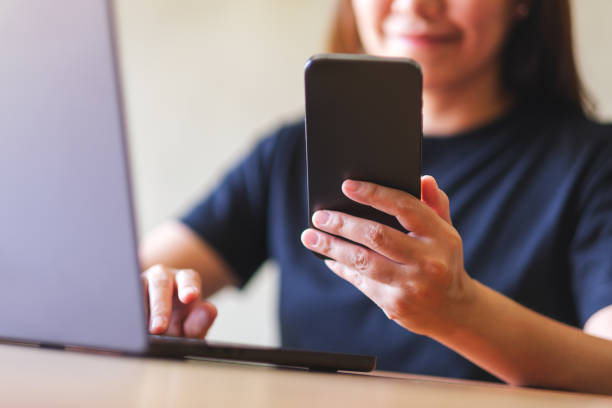 istock Closeup image of a young woman using smart phone and laptop computer 2057215649