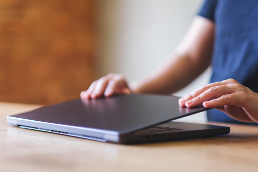 A woman opening or closing laptop computer, getting ready for work