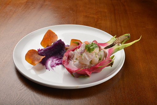 cold pink dragon fruit salad with root paste appetiser in plate on wood table fine dining western restaurant cafe halal menu