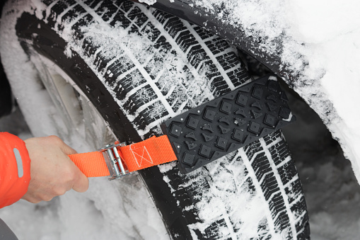 Senior Japanese male attaching a temporary snow chain to a winter tyre