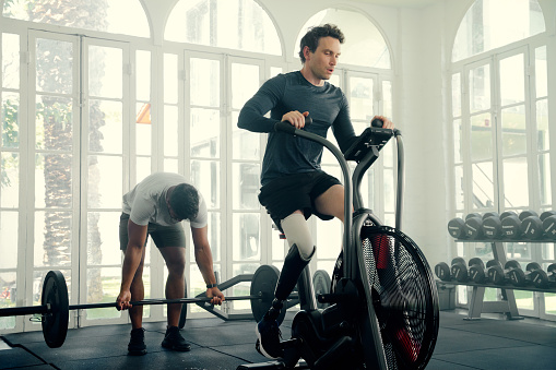 Two multiracial young men wearing sports clothing exercising with fitness equipment at the gym